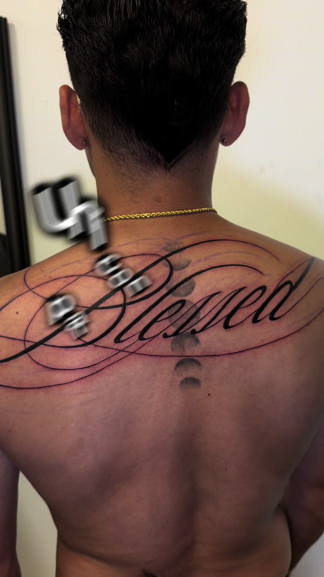 Tatuaje lettering con la palabra Blessed en caligrafía, en la espalda